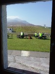 A view through a window of people sitting on outside tables in the sunshine